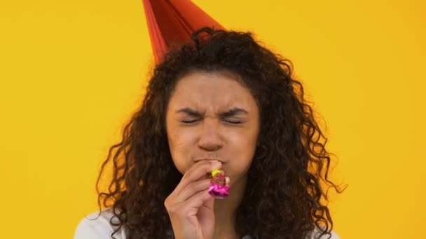 Happy girl blowing party horn, celebrating Birthday, isolated on background - Footage, Video