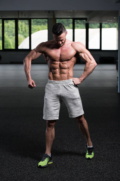 Retrato de un joven hombre físicamente en forma que muestra su cuerpo bien entrenado - Muscular atlético culturista modelo de fitness posando después de los ejercicios - Foto, imagen