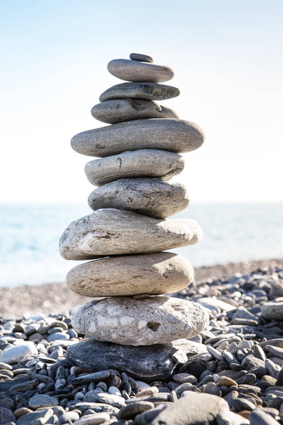 Felsen-Balancin oder Stein-Balancin, natürlich auf einem Strand mit dem Meer im Hintergrund balanciert - Foto, Bild