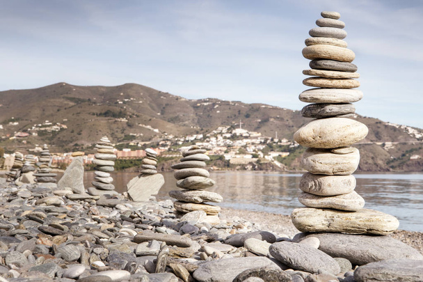 Balanceamento rochoso ou balancin de pedra, naturalmente equilibrado em uma praia com o mar atrás
 - Foto, Imagem