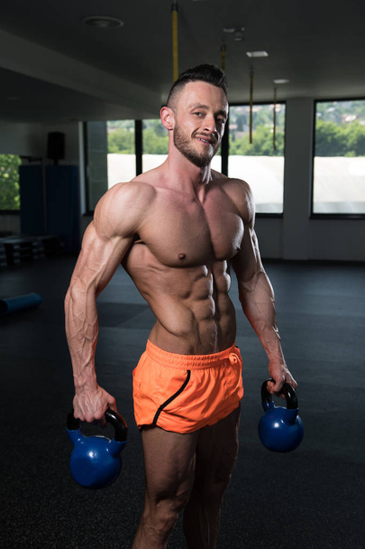 Man Exercising With Kettle Bell And Flexing Muscles - Muscular Athletic Bodybuilder Fitness Model Exercises - Foto, Imagem