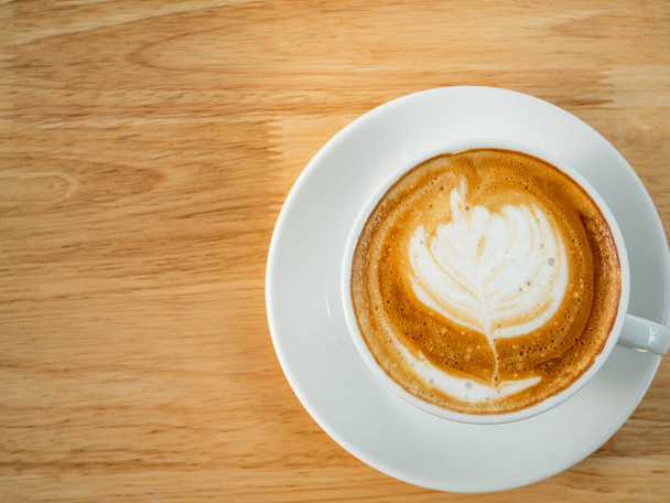 Hrnek latte umění kávy na dřevěné pozadí, pohled shora - Fotografie, Obrázek