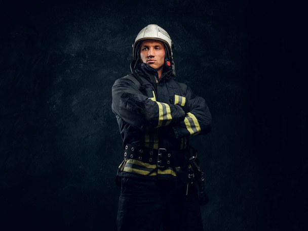 Portréja egy tűzoltó, egységes és a sisak áll, keresztezett kézzel, néz körül egy magabiztos megjelenés. - Fotó, kép