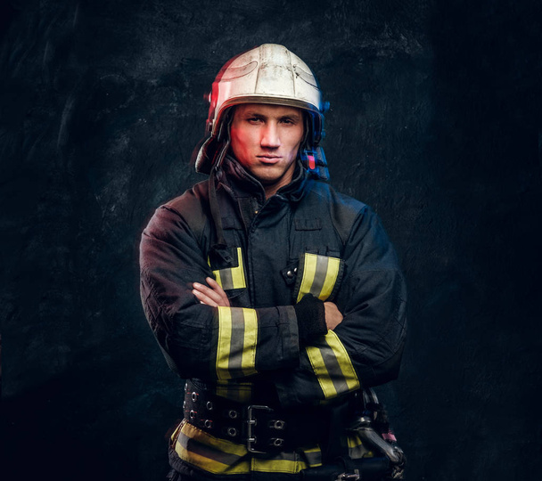 Жестокий пожарный в форме позирует перед камерой стоя со скрещенными руками и уверенным взглядом
. - Фото, изображение