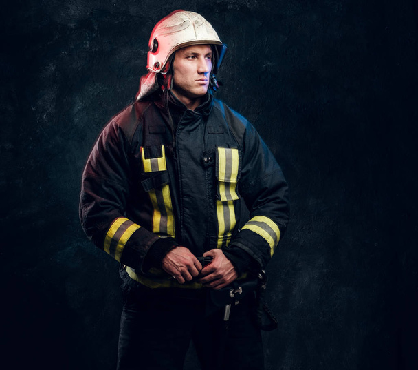 Portrait de pompier vêtu d'uniforme et casque de sécurité regardant latéralement avec un regard confiant
 - Photo, image