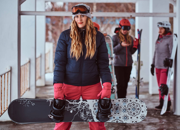 Норвежская женщина в теплой одежде и очках позирует со сноубордом на зимнем горнолыжном курорте
 - Фото, изображение