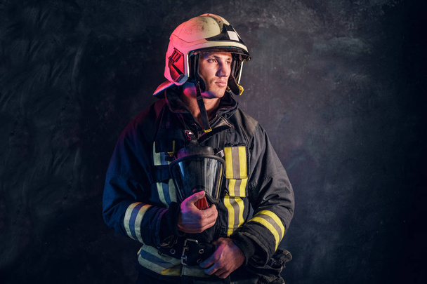 酸素マスクを保持していると自信のある顔つき横て制服・安全ヘルメットの消防士の肖像画. - 写真・画像