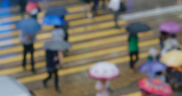 Visión borrosa de la gente cruzar la calle en día de lluvia
 - Foto, Imagen