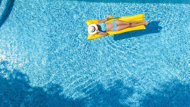 Güzel genç kız rahatlatıcı yüzme havuzunda şişme yatak üzerinde yüzüyor ve aile tatil tropikal tatil, hava uçak görünümü yukarıdan su eğlence var - Fotoğraf, Görsel
