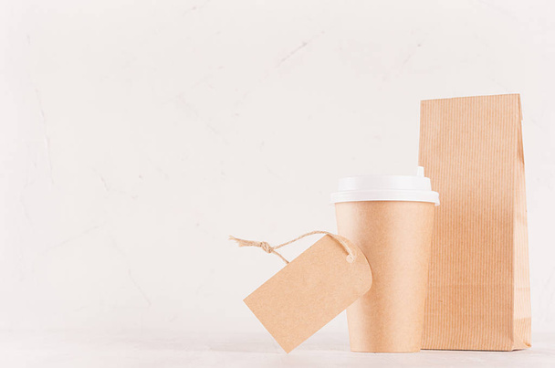 Coffee takeaway set mockup for brand - brown paper cup with blank label and craft bag on white wood board, copy space. - Foto, afbeelding
