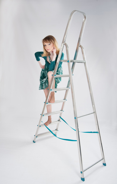 woman in a green dress standing on a stepladder - 写真・画像