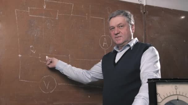 Senior teacher explains lesson, talking with students and writing - Filmati, video