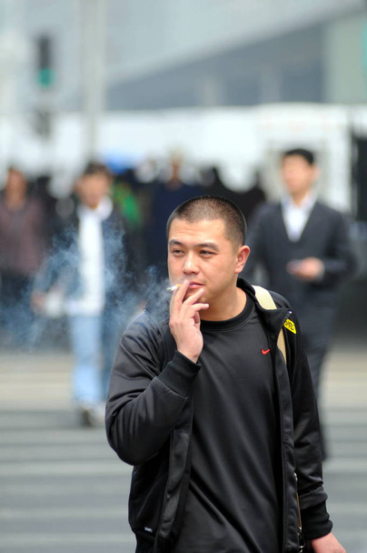 Un Chinois fume dans une rue de Pékin, Chine, 15 avril 2008
 - Photo, image