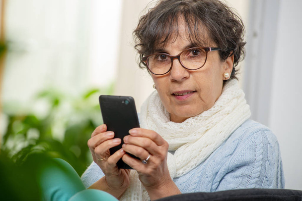 Retrato de la señora mayor morena utilizando la aplicación en su teléfono inteligente
 - Foto, Imagen