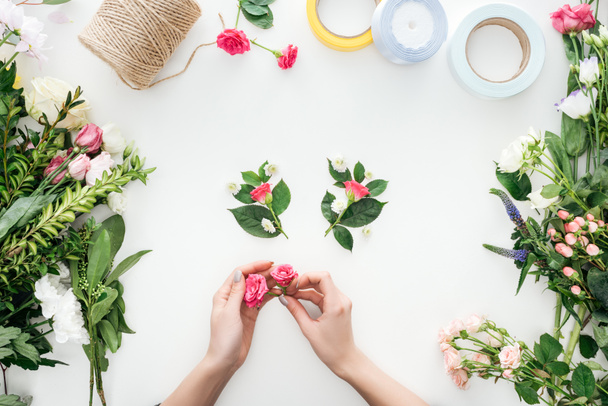 vue recadrée des mains féminines tenant des boutons de rose sur les boutonnières et entourées de fleurs sur fond blanc
 - Photo, image