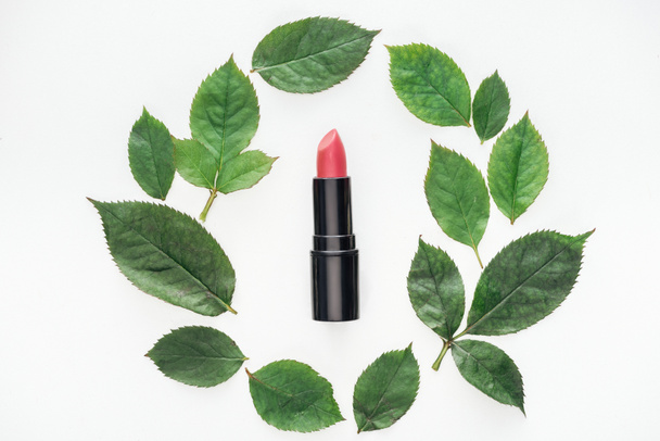 top view of pink lipstick surrounded rose leaves isolated on white - Fotoğraf, Görsel