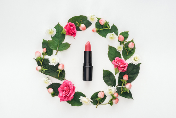 top view of circular composition with green leaves, flowers and pink lipstick isolated on white - 写真・画像