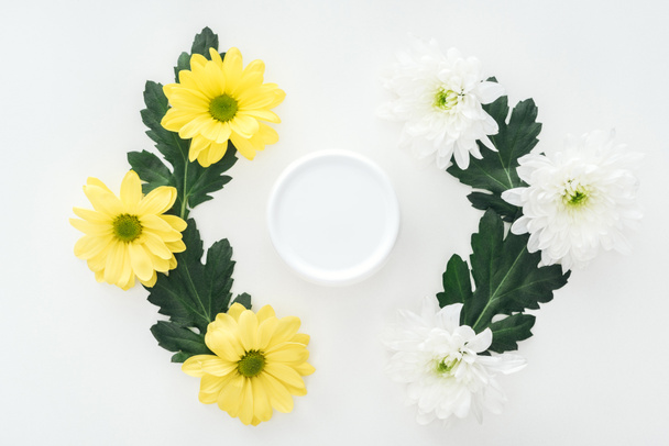 pohled shora kompozic s chryzantémy a kosmetický krém v lahvi na bílém pozadí - Fotografie, Obrázek