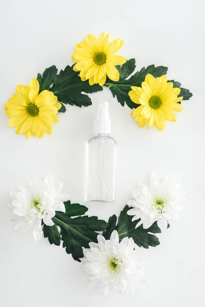 top view of empty spray bottle, white and yellow chrysanthemums on white background - Fotó, kép