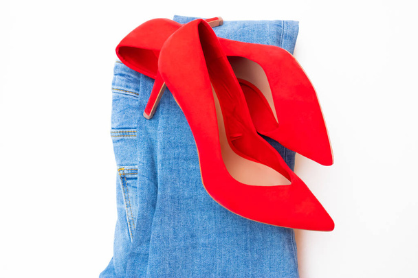Tacón alto zapatos rojos en tacones con vaqueros azules sobre fondo blanco
 - Foto, imagen