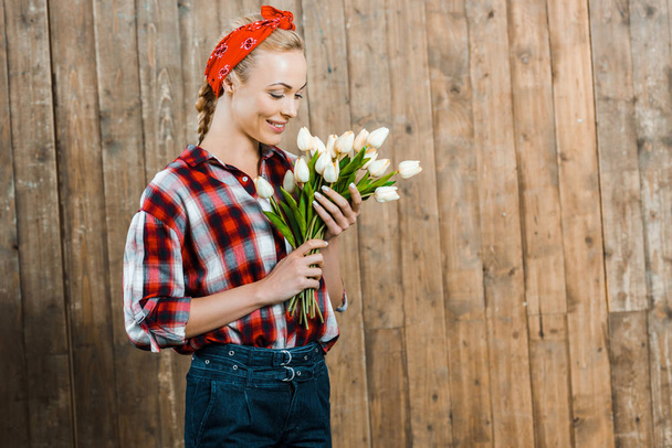 Veselá žena s úsměvem při pohledu na tulipány  - Fotografie, Obrázek
