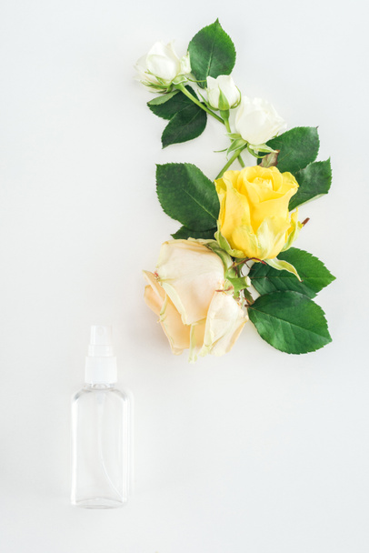 top view of composition with roses and empty spray bottle on white background - Фото, изображение