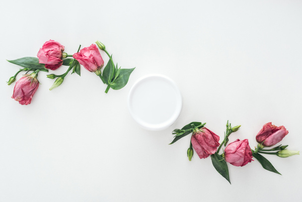 το top view συνθέσεις με ροζ κρέμα eustoma και την ομορφιά σε μπουκάλι σε λευκό φόντο - Φωτογραφία, εικόνα