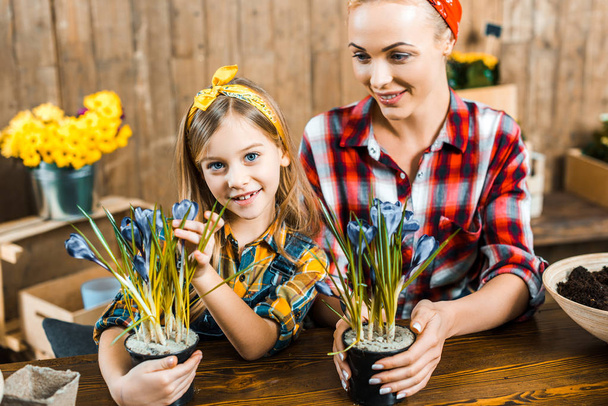 happy mother looking at daughter and holding pot with flowers - Foto, Imagem