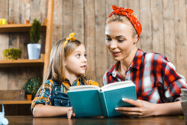 beautiful mother reading book to cute daughter - Photo, Image