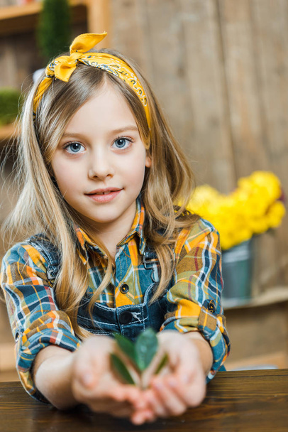 selective focus of cute child holding green leaves in hands  - Foto, Bild