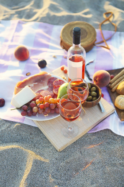 Picknick buiten met rose wijn vruchten vlees en kaas. Zonsondergang - Foto, afbeelding