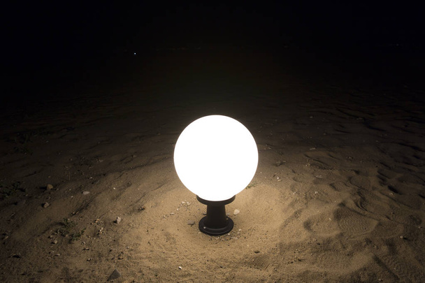 close up view of standard small garden lamp on sandy beach at night - Photo, Image