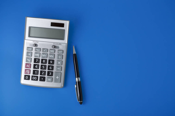 Calculatrice Sliver sur fond bleu avec stylo noir, pose plate avec espace
 - Photo, image