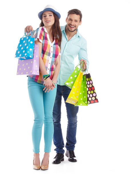 Attractive young couple with shopping bags on white background - Foto, imagen