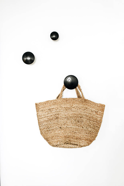 Panier sac paille sur cintre noir à fond blanc. Concept de design d'intérieur nordique moderne minimal
. - Photo, image