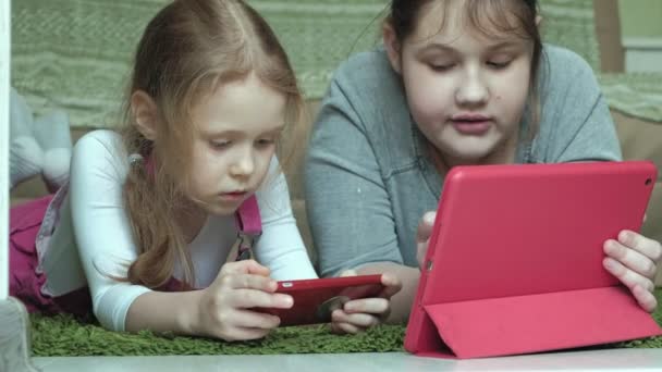 αδελφές κορίτσια που παίζουν για το tablet στο δωμάτιο, web-surfing, υπόλοιπο - Πλάνα, βίντεο