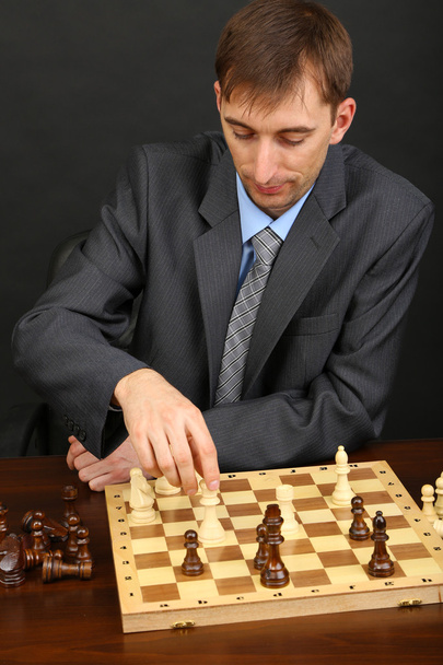Young business man playing chess on black background - Фото, изображение