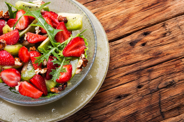 Cuenco de ensalada con fresa, rúcula y kiwi en mesa de madera.Desayuno vegano saludable
 - Foto, Imagen