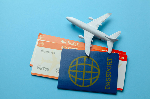 Bilhetes para avião e passaporte com modelo de avião de passageiros em fundo azul
 - Foto, Imagem