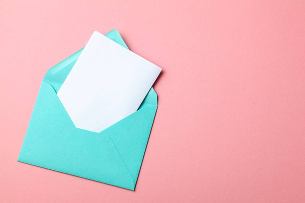 Green envelope and blank letter on pink background. mock-up. - Foto, afbeelding