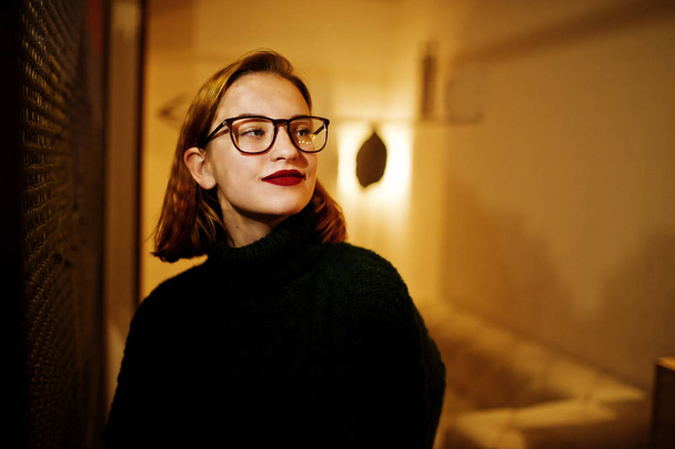 Cheerful young beautiful redhaired woman in glasses, wear on green warm wool sweater,  posed at cafe. - Photo, Image