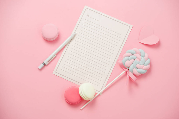 Un foglio bianco di carta per il messaggio alla persona amata, macaron, caramelle su sfondo rosa. Concetto di giorno di donne felici. Scherzi?
 - Foto, immagini