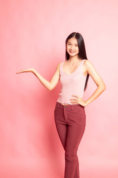 Young Asian woman present with her hand on pink background - Foto, Imagem