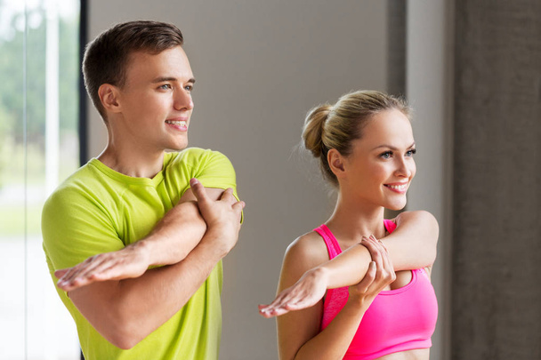 smiling man and woman exercising in gym - Фото, изображение