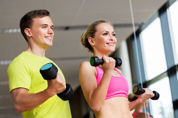 couple with dumbbells exercising in gym - Foto, Imagem