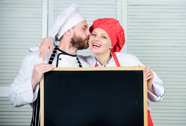 Couple with blackboard for advertisement. Lovely family at kitchen. Family restaurant. Family day. Couple in love cooking together. Family values. Share joy. Man and woman chef cooking food together - Foto, Imagem