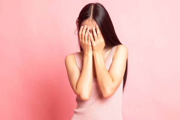 Sad young Asian woman cry with palm to face on pink background - 写真・画像