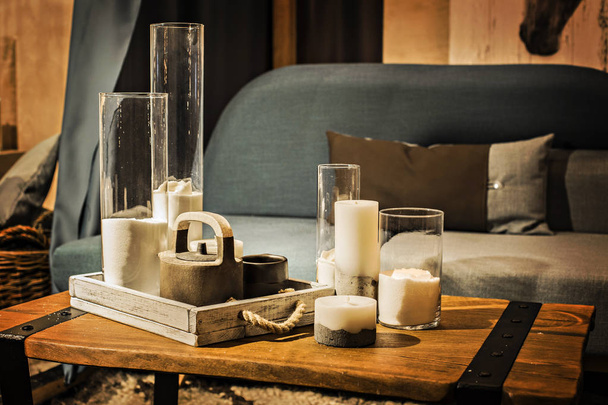 Wohnungselemente: gemütliches Sofa in Grau- und Blautönen mit Kissen, Holztisch mit Kerzen und Tee-Set - Foto, Bild