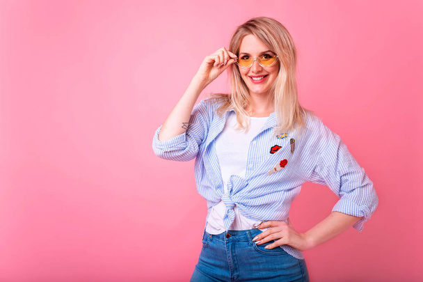 Portrait of a happy cheerful girl, young blonde woman showing peace gesture with two hands isolated over pink background - Foto, Imagem