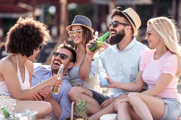 Group of people enjoying in a good mood and picnic on the beach. Lifestyle, fun,happiness and vacation concept. - Photo, Image